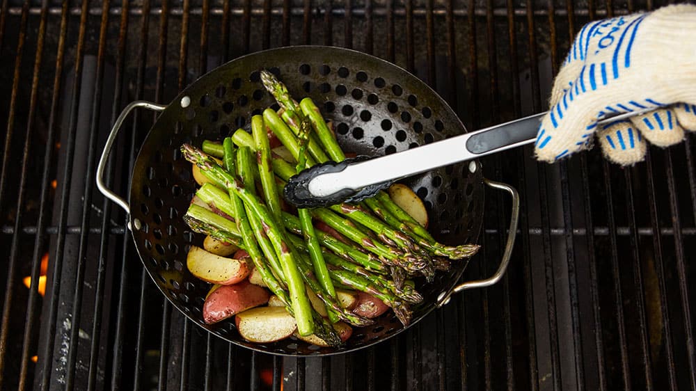 Mixing new potatoes and asparagus spears in grill basket