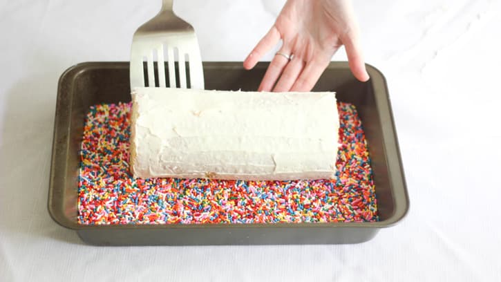rolling cake in pan filled with sprinkles