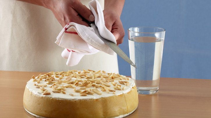 sprinkling top of cheesecake with almonds