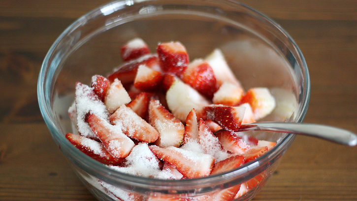 cut up strawberries in bowl sprinkled with sugar