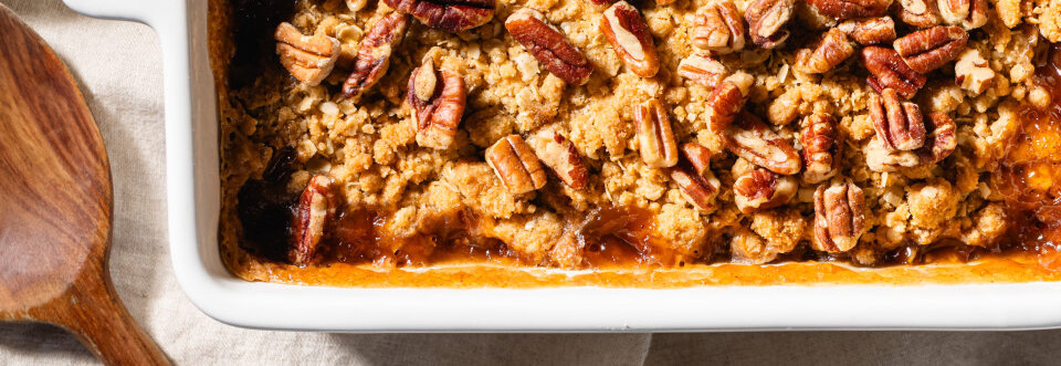 Top down shot of apple crumble bars with oats and pecans on top in a white pan