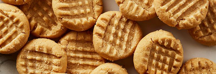 Top-down image of classic peanut butter cookies on a countertop with a red and white napkin on the left side.