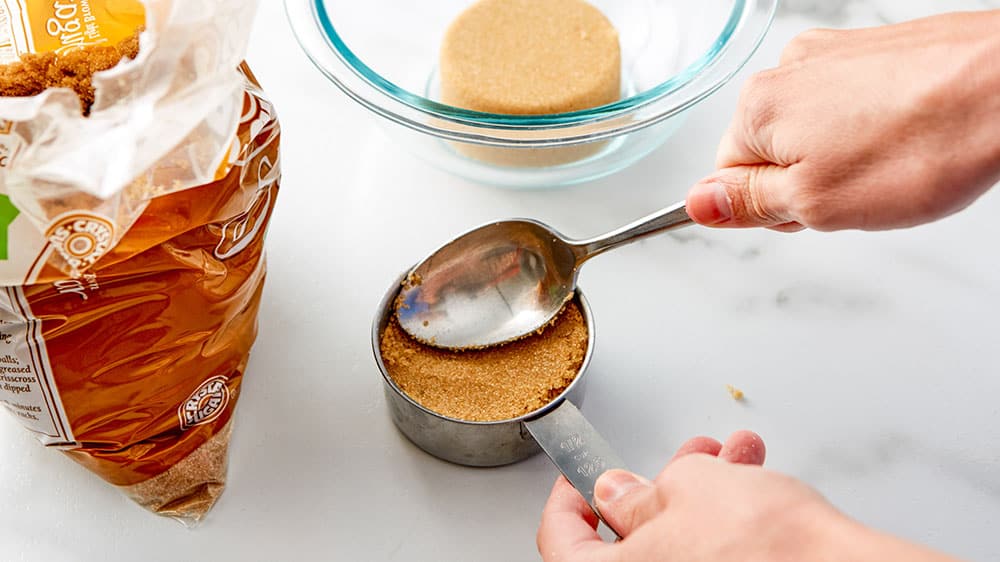 packing down brown sugar in measuring cups