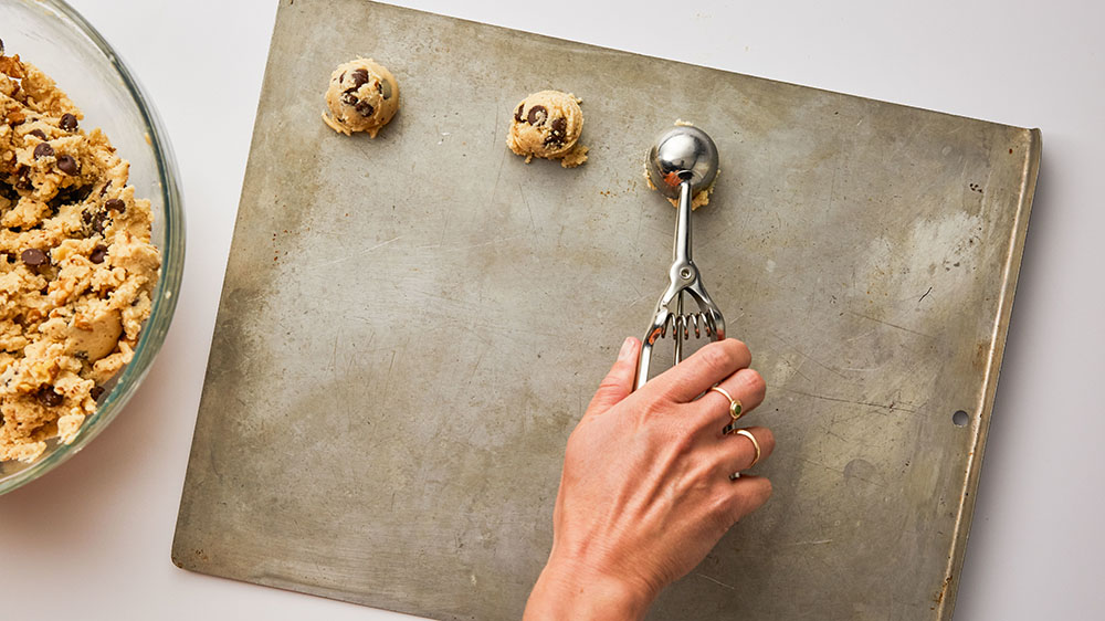using cookie scoop to place dough on cookie sheet