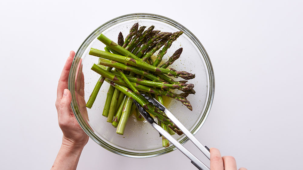 tossing asparagus with oil and seasonings