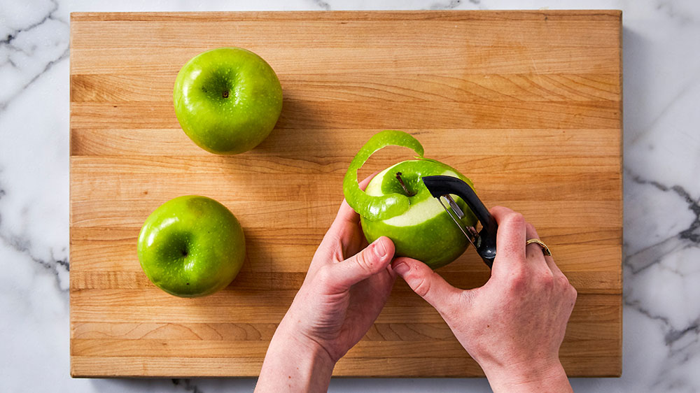 Peeling Granny Smith apples on a cutting board