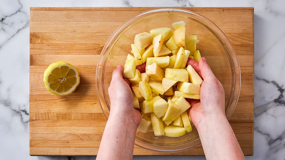  Tossing chopped apples in lemon juice and water to prevent browning.