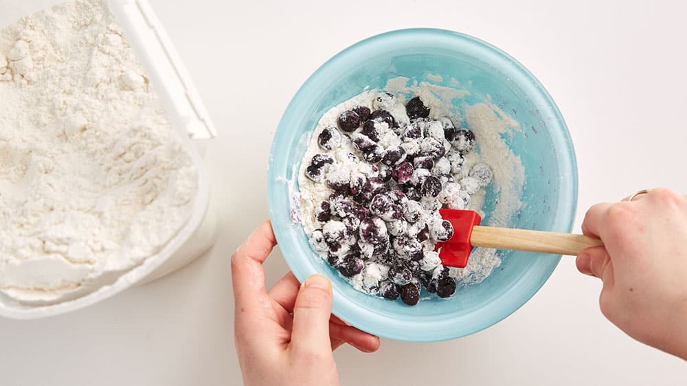 frozen blueberries being tossed with flour