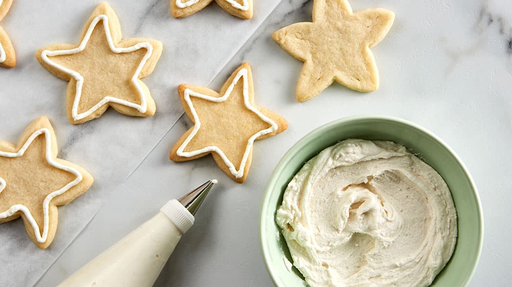 Piping bag, bowl of frosting and piped star cookies