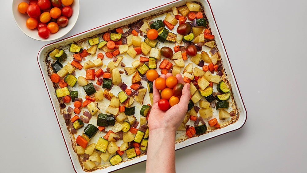 adding tomatoes to the sheet pan