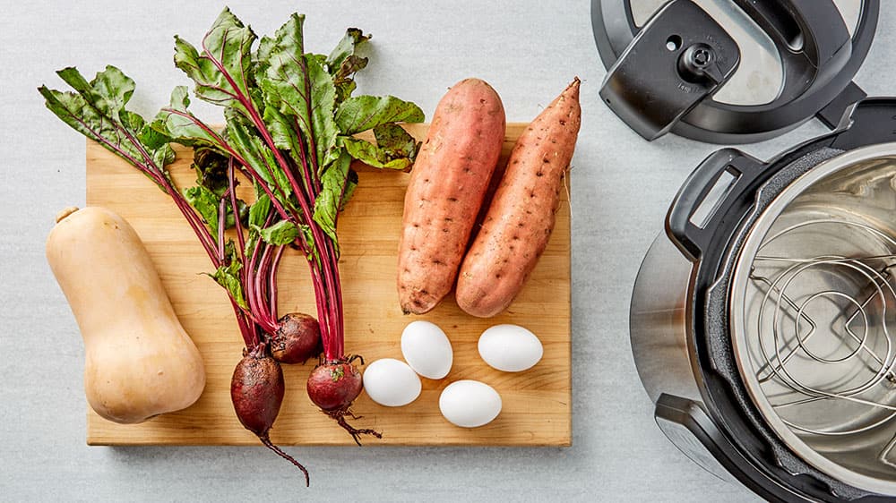 Butternut squash, beets, eggs, sweet potatoes on a cutting board 