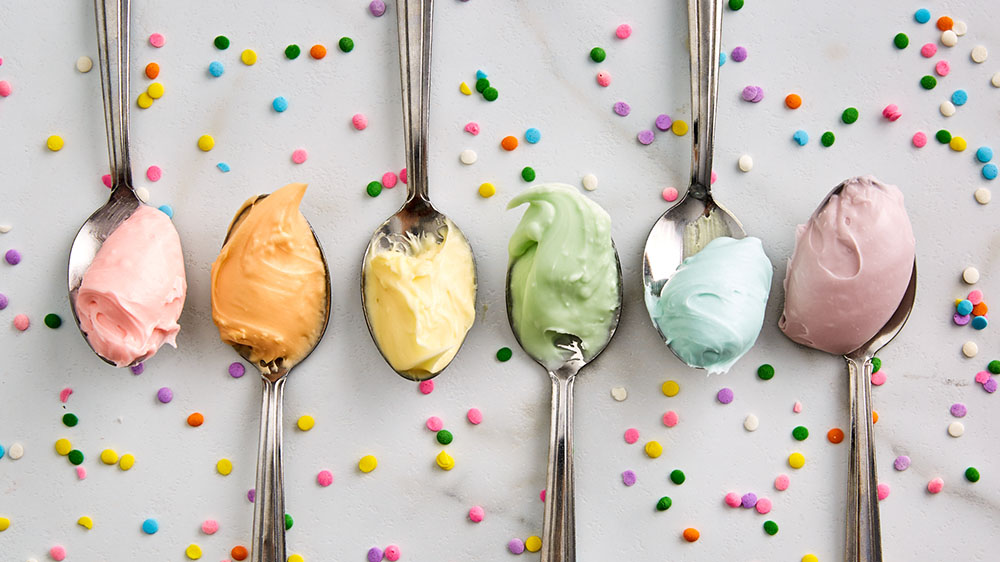 Pastel frosting on spoons with sprinkles. 