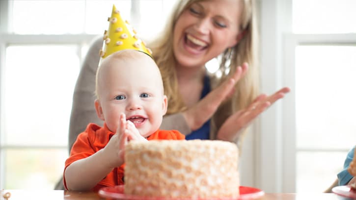 mom clapping behind baby with Cheerios cake