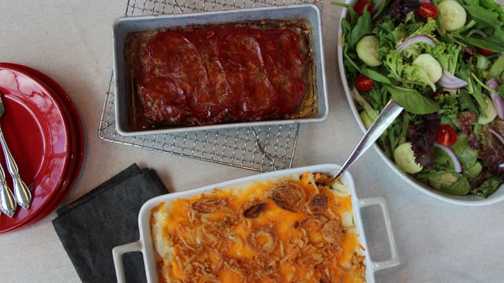 meatloaf, salad and potato bake with plates and silverware on table