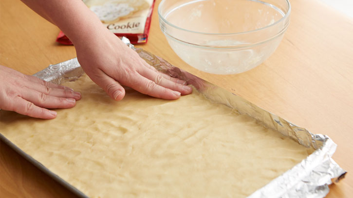 pressing dough into bottom of pan