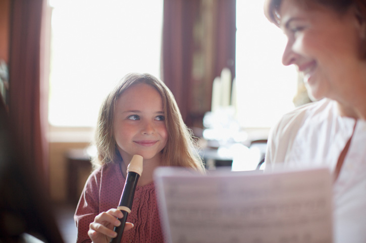 Child playing recorder with older woman
