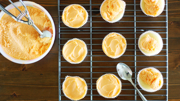scoops of orange sherbet on top of baked cupcakes