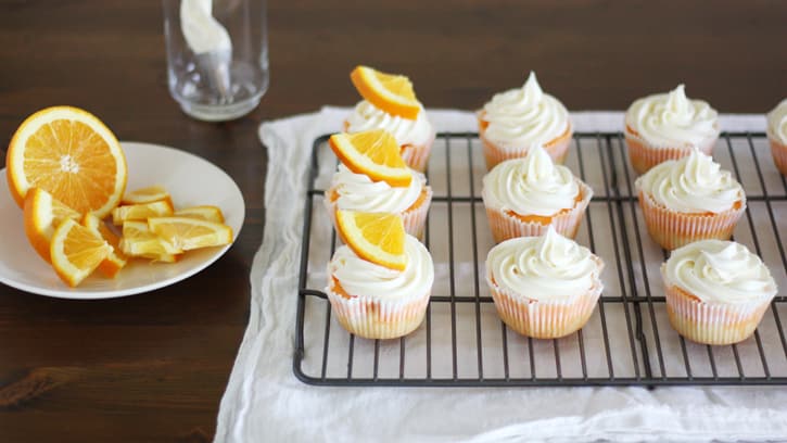 cupcakes topped with white frosting and orange slice
