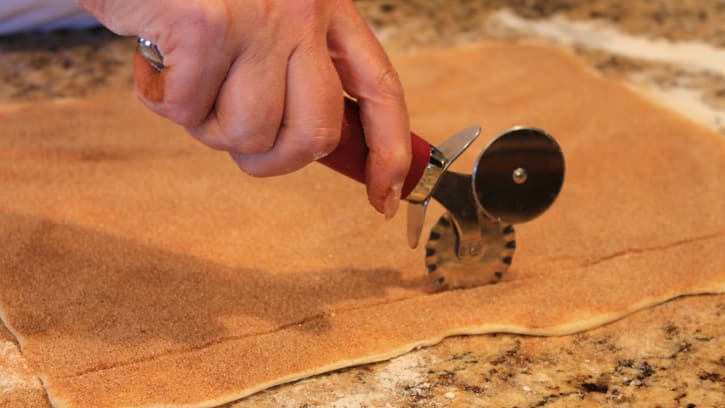 cutting strips of dough with pastry cutter