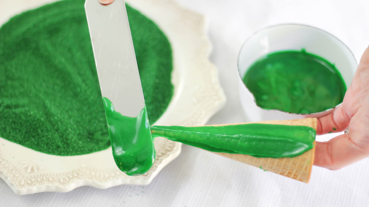 spreading green frosting on sugar cones