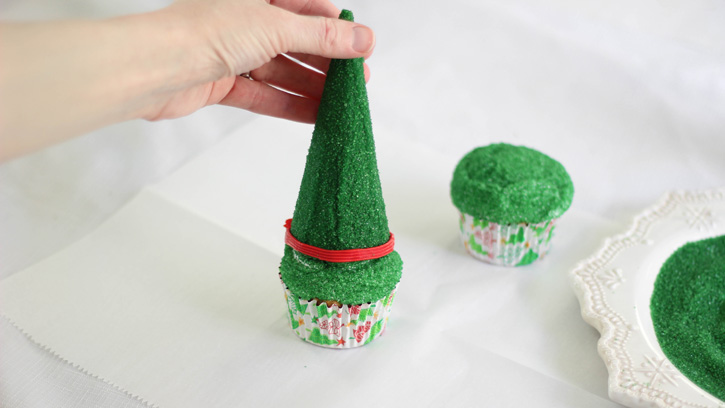 placing green cone on top of cupcake