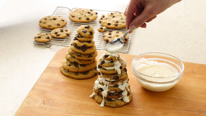 drizzling frosting over stack of cookies