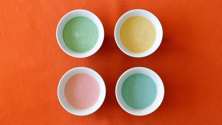 four bowls with green, blue, yellow and red batters