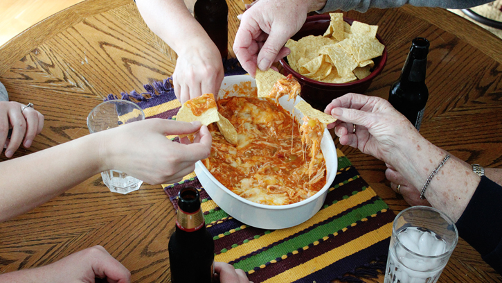 people around a table dipping into chicken enchilada dip