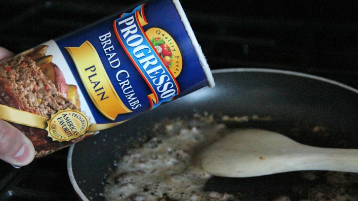 Pouring Progresso bread crumbs into a skillet