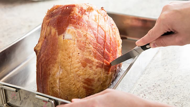 scoring the rind of the ham to create a criss-cross pattern