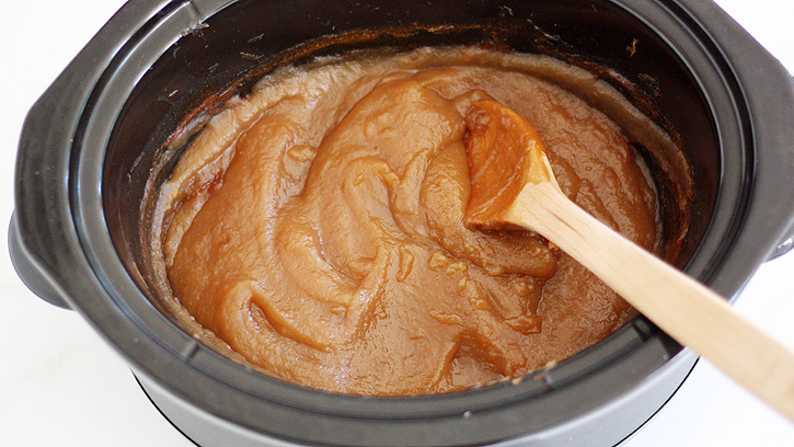 stirring apple butter in slow cooker