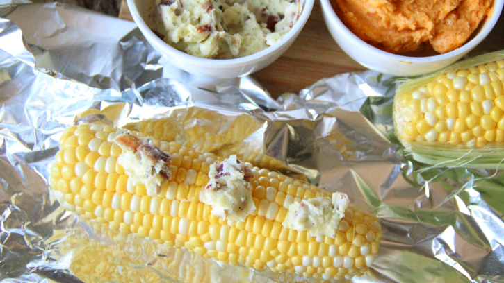adding butter to corn and wrapping in aluminum foil